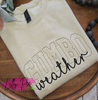 Beige sweatshirt with 'Gumbo weather' text on a wooden surface, featuring Lilly Pie Creations logo.